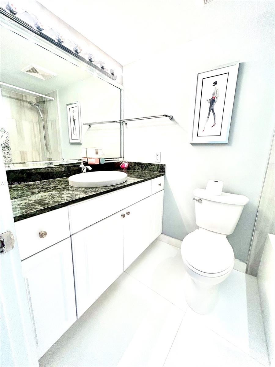 200 Diplomat Parkway, Unit 721 Hallandale Beach, FL 33009 - Photo 8 of 47 a bathroom with a granite countertop toilet sink and mirror