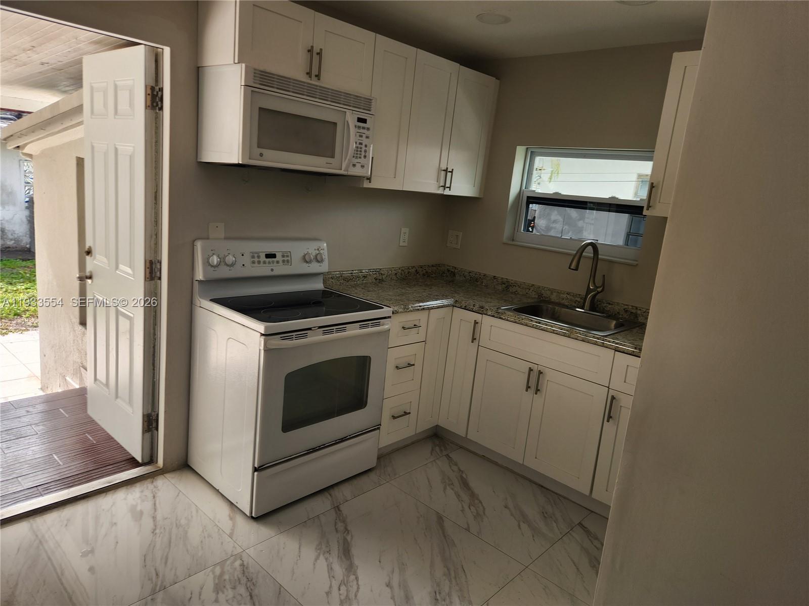 342 East 46th Street, Unit 2 Hialeah, FL 33013 - Photo 5 of 15 a kitchen with cabinets appliances and a window