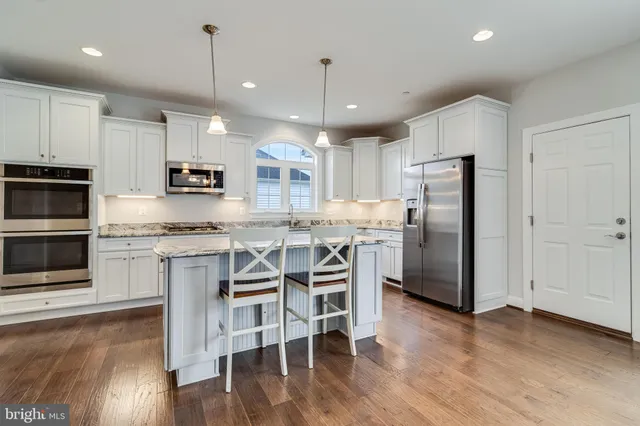 a kitchen with stainless steel appliances kitchen island granite countertop a refrigerator a stove microwave and white cabinets