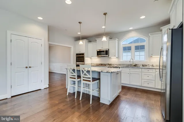 a kitchen with kitchen island granite countertop a sink cabinets and wooden floor