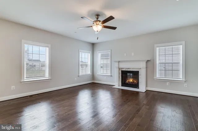 a view of an empty room with wooden floor fireplace and a window