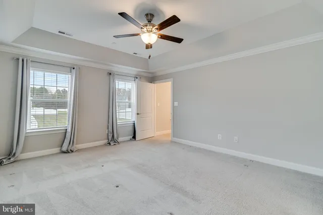 an empty room with chandelier fan and windows