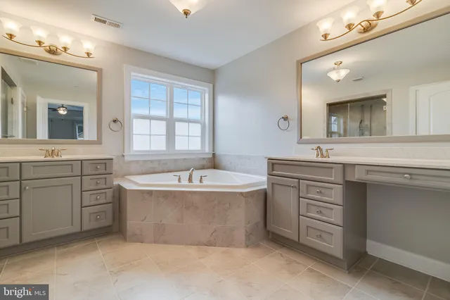 a spacious bathroom with a tub double vanity sink and mirror