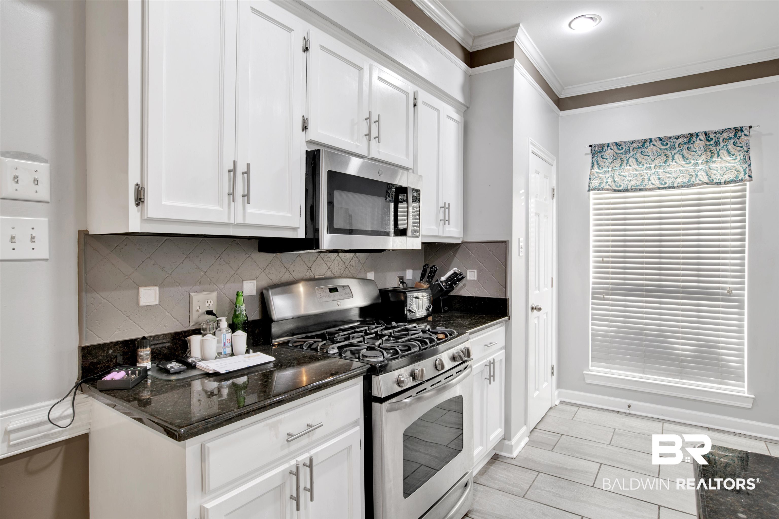 445 Wedgefield Drive South Mobile, AL 36608 - Photo 13 of 36 Kitchen with dark stone countertops, appliances with stainless steel finishes, decorative backsplash, white cabinets, and ornamental molding