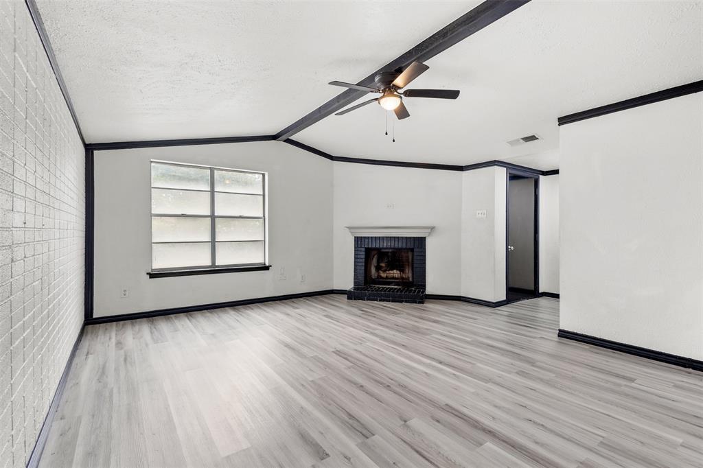 2802 Spring Valley Drive Bedford, TX 76021 - Photo 11 of 24 an empty room with wooden floor fireplace and windows