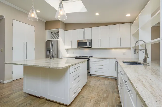 a kitchen with stainless steel appliances granite countertop a sink a stove and a refrigerator