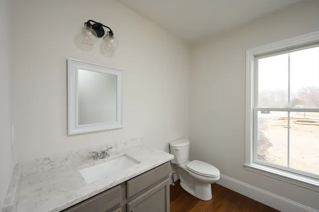 a bathroom with a toilet sink vanity and mirror