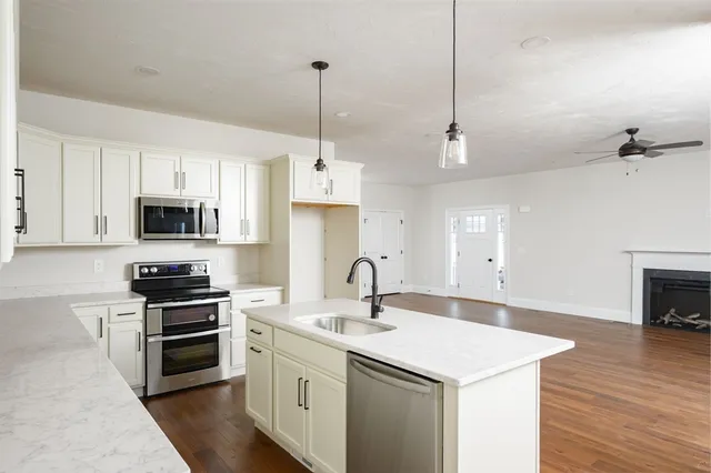 a kitchen with stainless steel appliances granite countertop a sink a stove and a wooden floors
