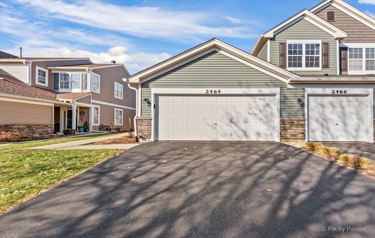 2464 Golf Ridge Circle, Unit 2464 Naperville, IL 60563 - Photo 2 of 28 a front view of a house with a yard and garage