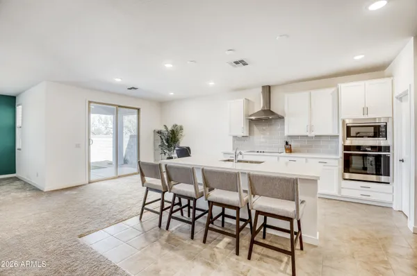 a kitchen with kitchen island a dining table chairs stainless steel appliances and cabinets