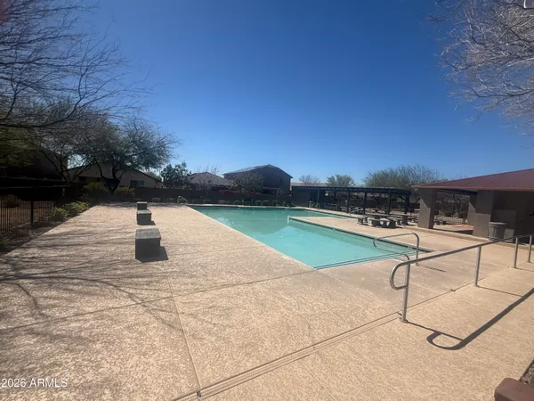 a view of swimming pool with seating area and trees in the background