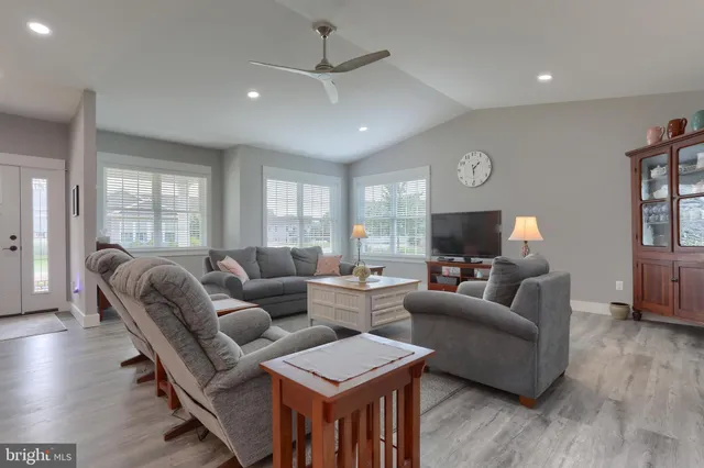 a living room with furniture a ceiling fan and a flat screen tv