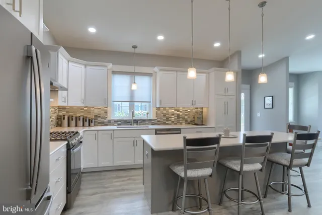a kitchen with kitchen island a dining table chairs stainless steel appliances and cabinets