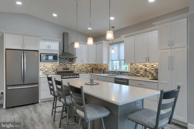 a kitchen with a dining table chairs stainless steel appliances and cabinets