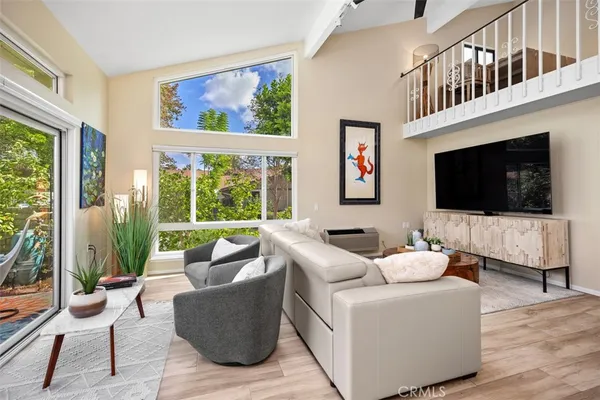 a living room with furniture a flat screen tv and a floor to ceiling window
