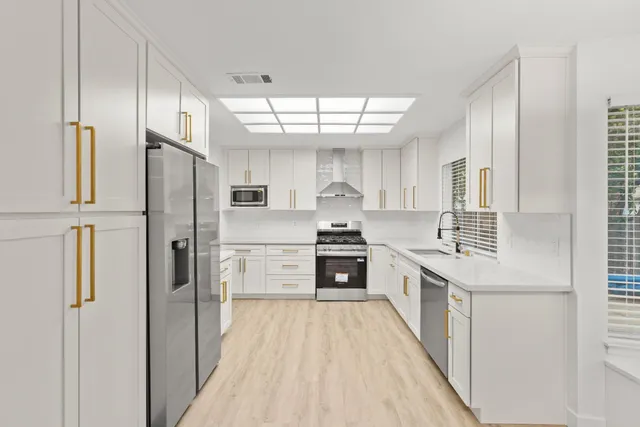 a kitchen with stainless steel appliances a sink a stove a refrigerator and cabinets