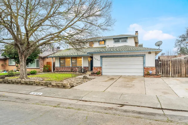 a view of a white house with a large space and a large tree