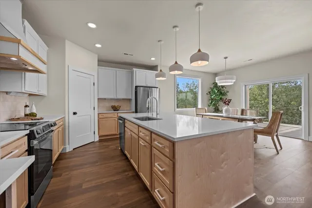 a kitchen with stainless steel appliances granite countertop a stove a sink and a white wooden cabinets