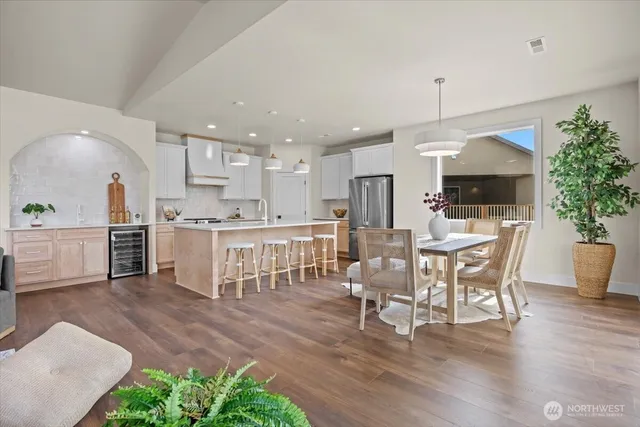 a kitchen with stainless steel appliances kitchen island granite countertop a table chairs sink and cabinets