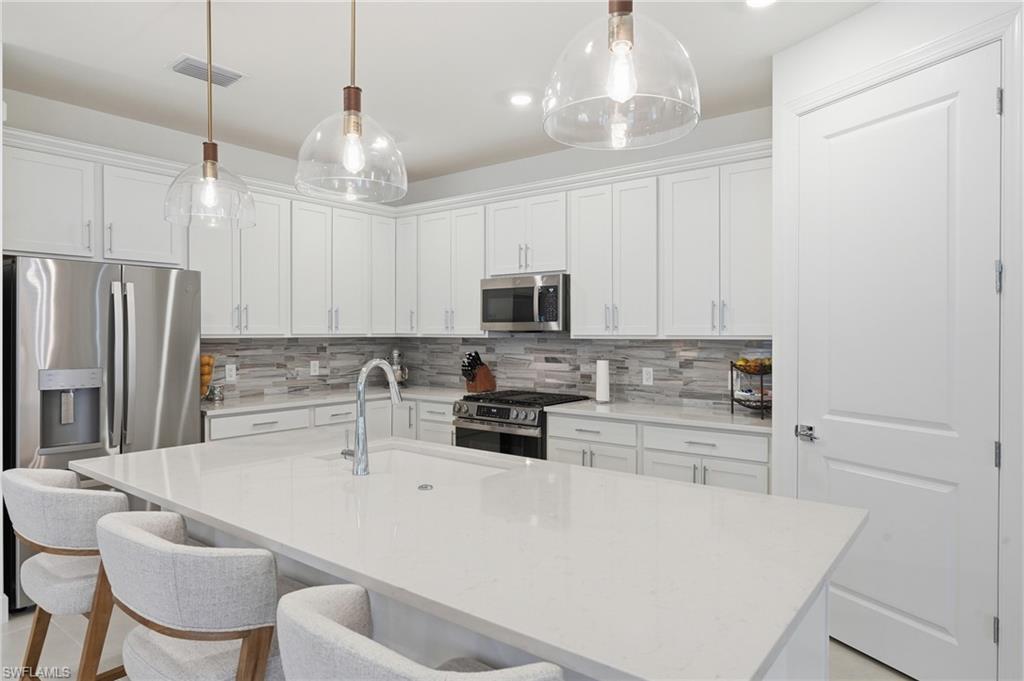 18364 Ridgeline Drive Estero, FL 33928 - Photo 15 of 50 a kitchen with a refrigerator a stove a sink and white cabinets