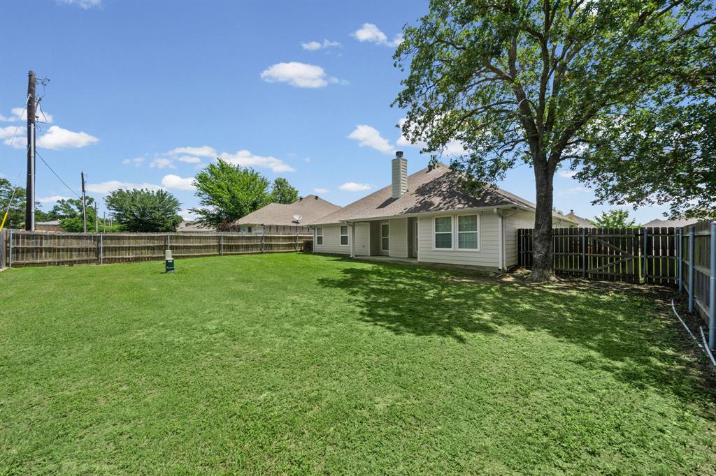 229 Firefly Drive Springtown, TX 76082 - Photo 24 of 33 Expansive backyard featuring a manicured lawn, established tree, and wood privacy fencing