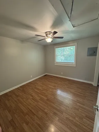 an empty room with wooden floor ceiling fan and windows