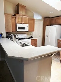 24922 Muirlands Lake, Unit 115 Lake Forest, CA 92630 - Photo 3 of 17 a kitchen with kitchen island a sink a stove a refrigerator and cabinets