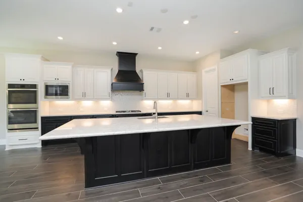 a large kitchen with stainless steel appliances a large counter top a stove and a sink
