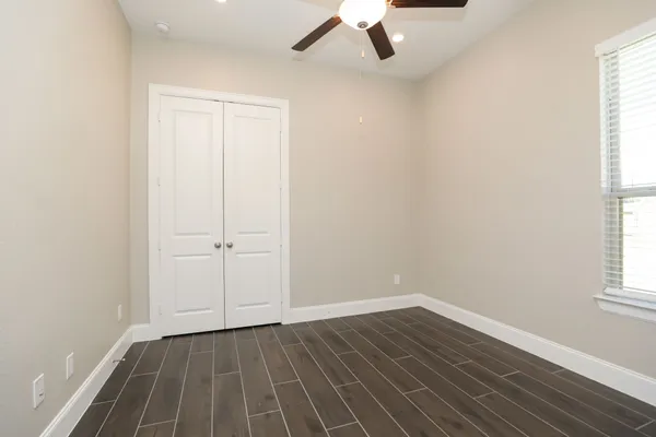 an empty room with wooden floor cabinet and windows