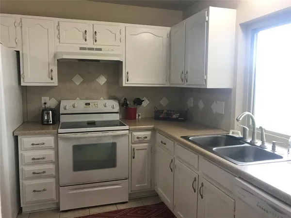 a kitchen with white cabinets white stainless steel appliances and sink