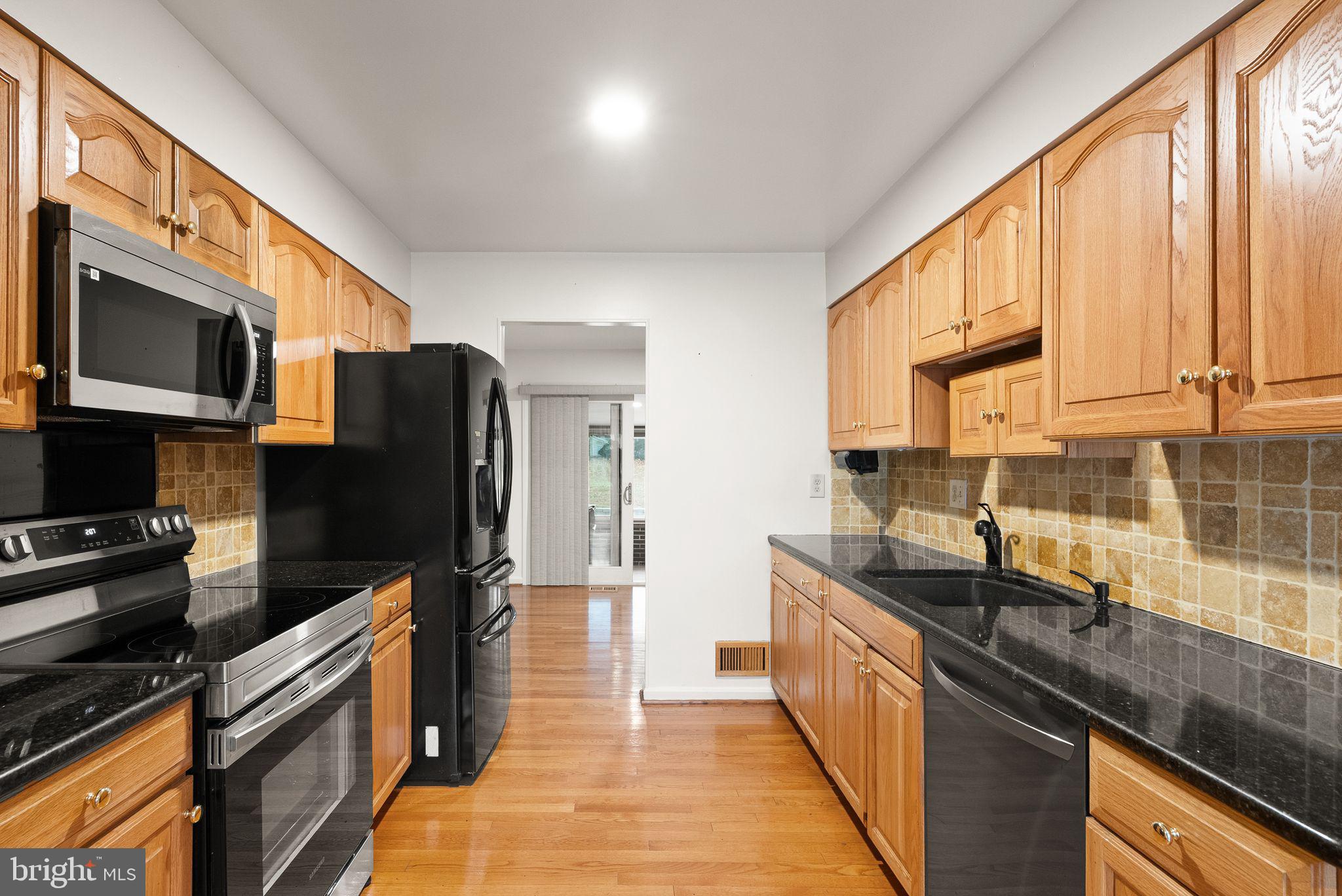 8522 Tysons Court Vienna, VA 22182 - Photo 6 of 27 a kitchen with stainless steel appliances granite countertop a stove top oven microwave and refrigerator