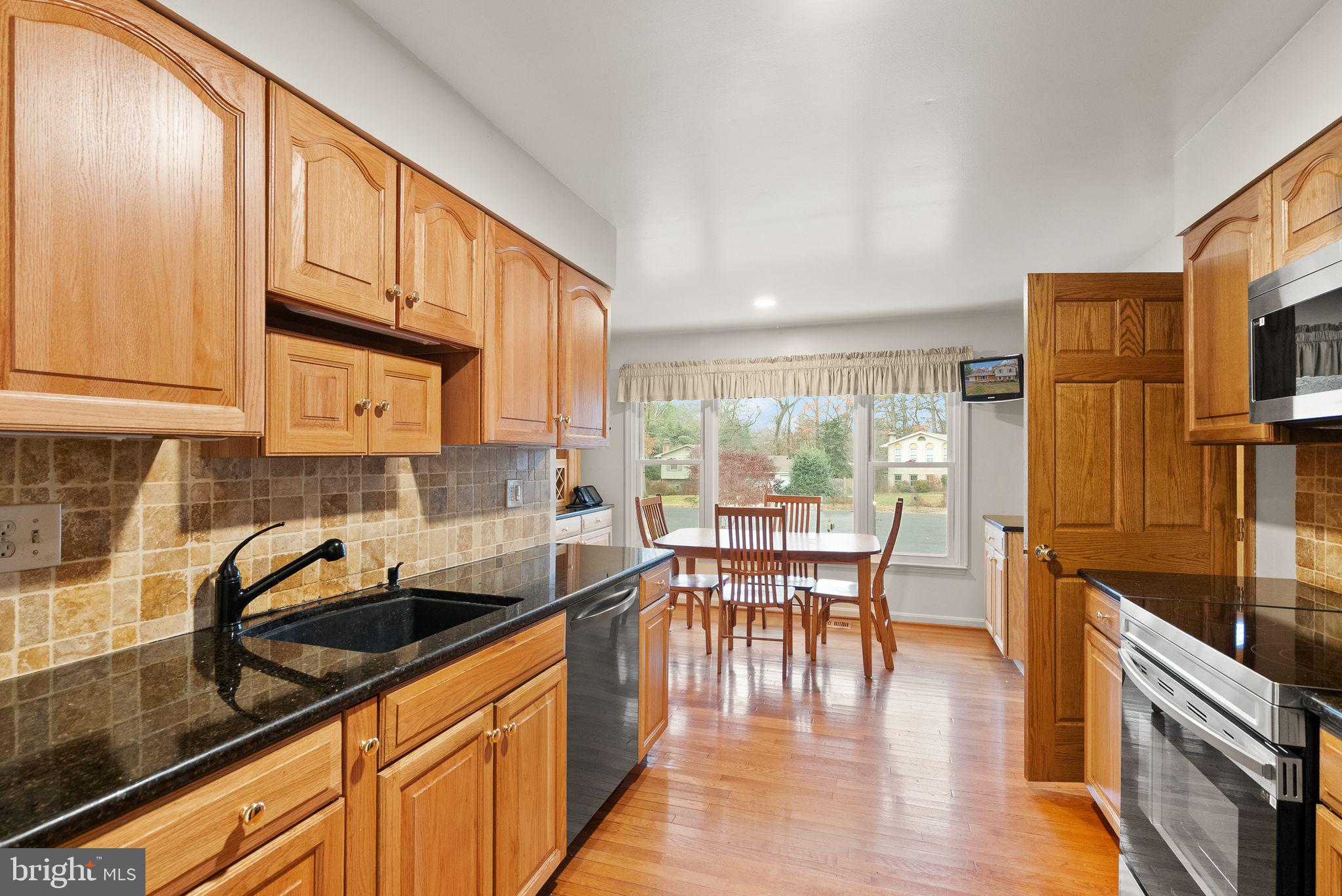 8522 Tysons Court Vienna, VA 22182 - Photo 7 of 27 a kitchen with granite countertop a stove a sink a dining table and chairs