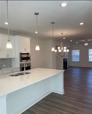 a kitchen with kitchen island a sink stainless steel appliances and wooden floor