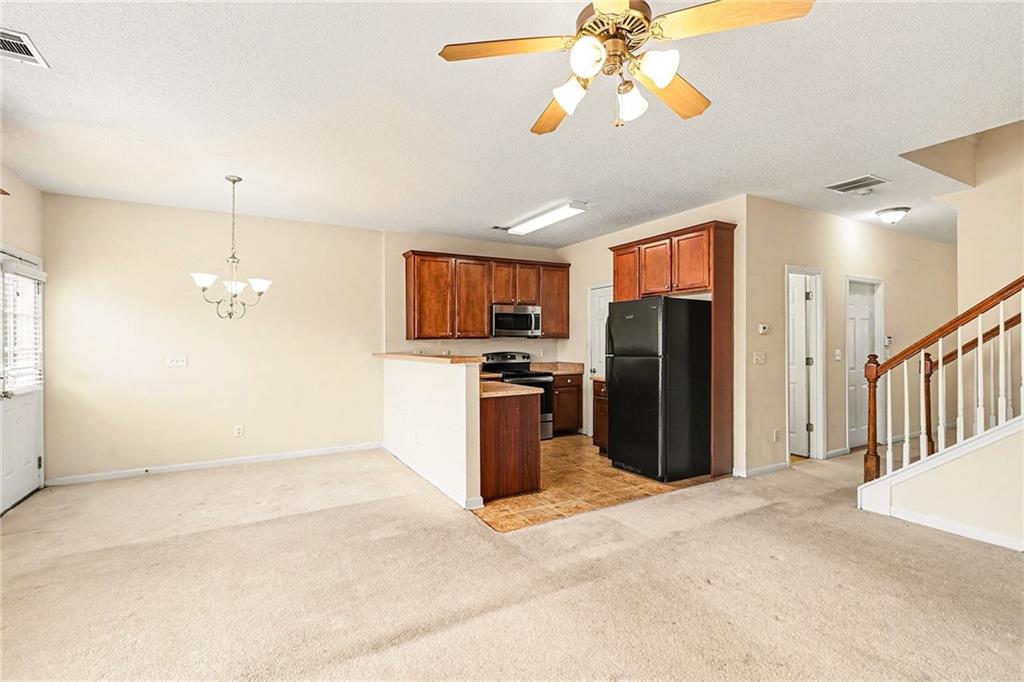 7676 Rutgers Circle Fairburn, GA 30213 - Photo 11 of 33 a view of a kitchen with a refrigerator a microwave and a chandelier