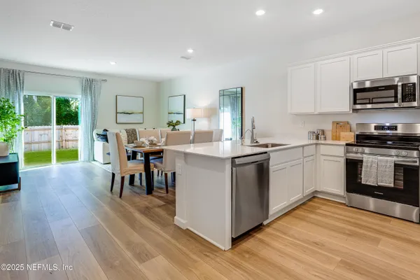 a kitchen with stainless steel appliances granite countertop a stove top oven a sink dishwasher a dining table and chairs with wooden floor