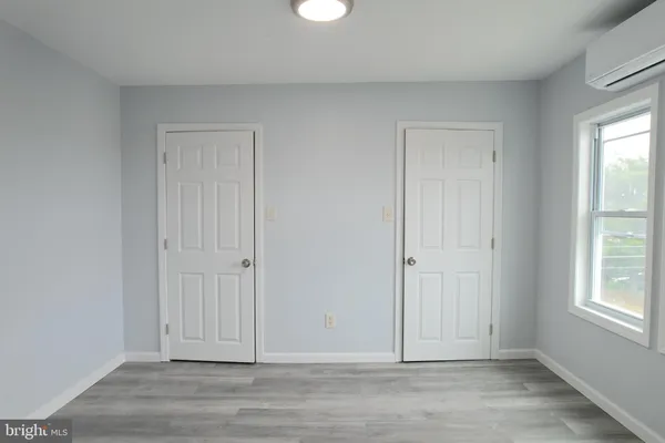 an empty room with wooden floor cabinet and windows
