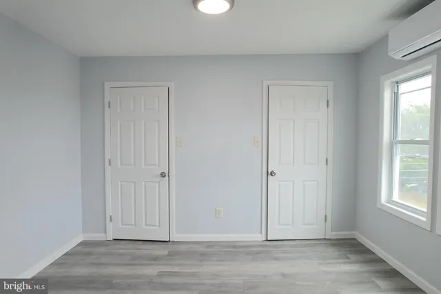 an empty room with wooden floor cabinet and windows
