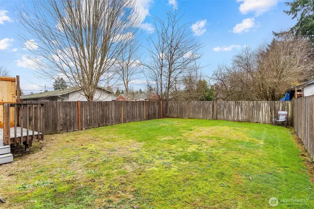 a view of backyard with deck and wooden fence