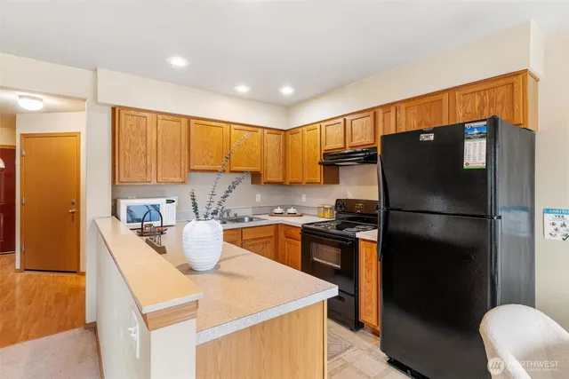 a kitchen with stainless steel appliances granite countertop a refrigerator a sink a stove a dining table and chairs