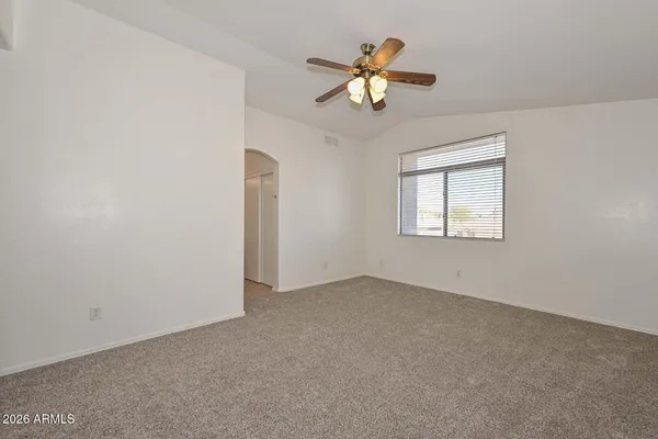 an empty room with a chandelier fan and windows