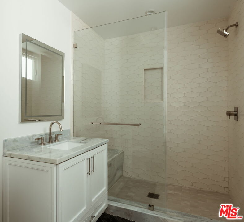 10725 Ashton Avenue, Unit 101 Los Angeles, CA 90024 - Photo 34 of 40 a bathroom with a granite countertop sink a mirror and shower