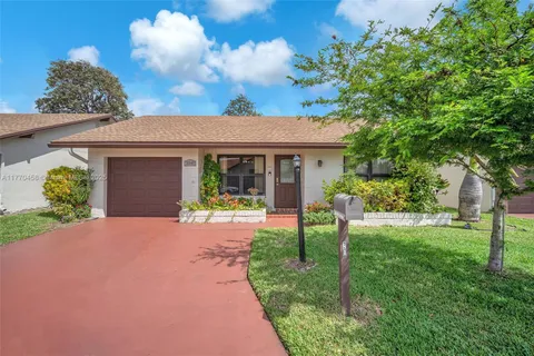 a front view of a house with a yard and potted plants