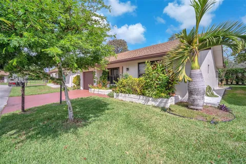 a front view of a house with a yard and tree