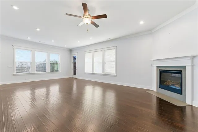 an empty room with wooden floor fireplace and windows