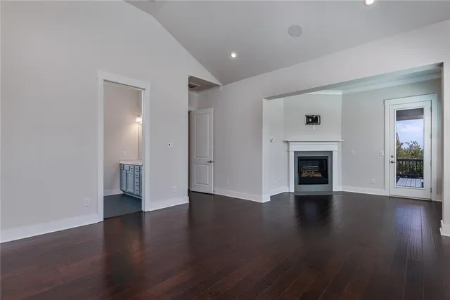 an empty room with wooden floor fireplace and windows