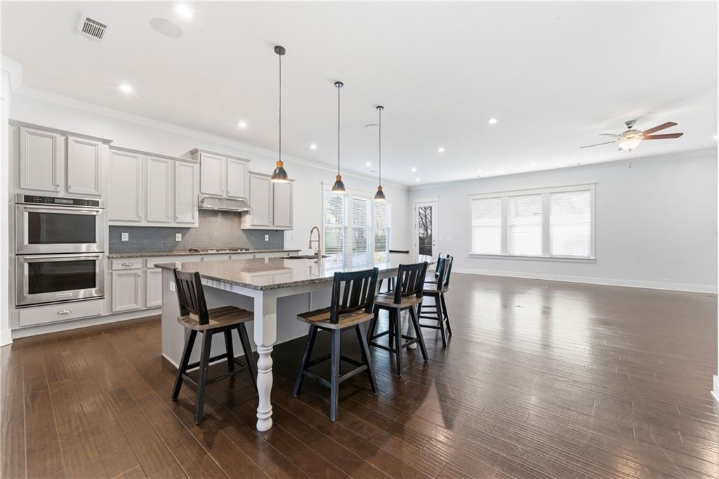 601 Long Leaf Way Canton, GA 30114 - Photo 8 of 42 a kitchen with stainless steel appliances granite countertop a stove a refrigerator a kitchen island a dining table and chairs with wooden floor