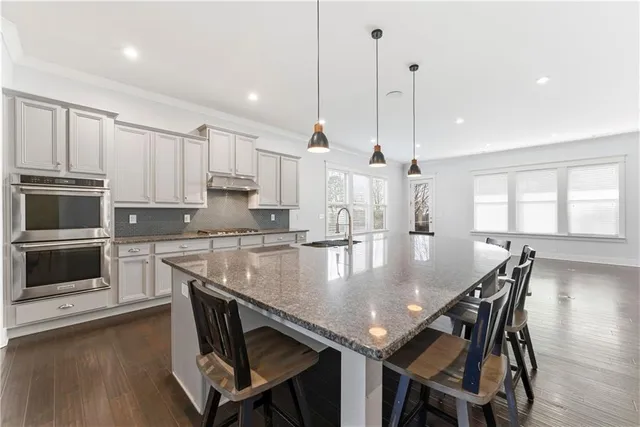 a kitchen with stainless steel appliances granite countertop a stove a kitchen island a stove a table and chairs