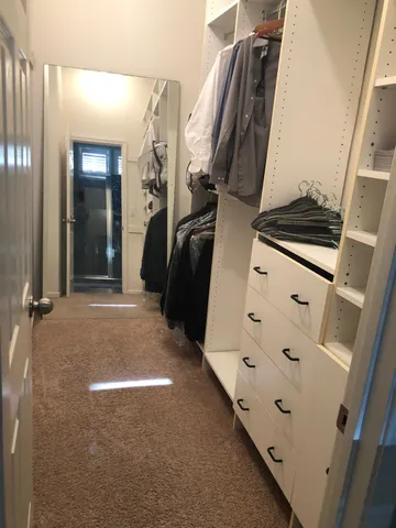 a view of walk in closet with clothes and shoes
