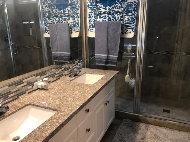 a bathroom with a granite countertop sink a mirror and shower