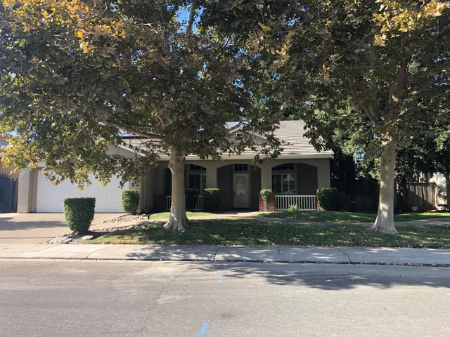 a front view of a house with yard garage and tree